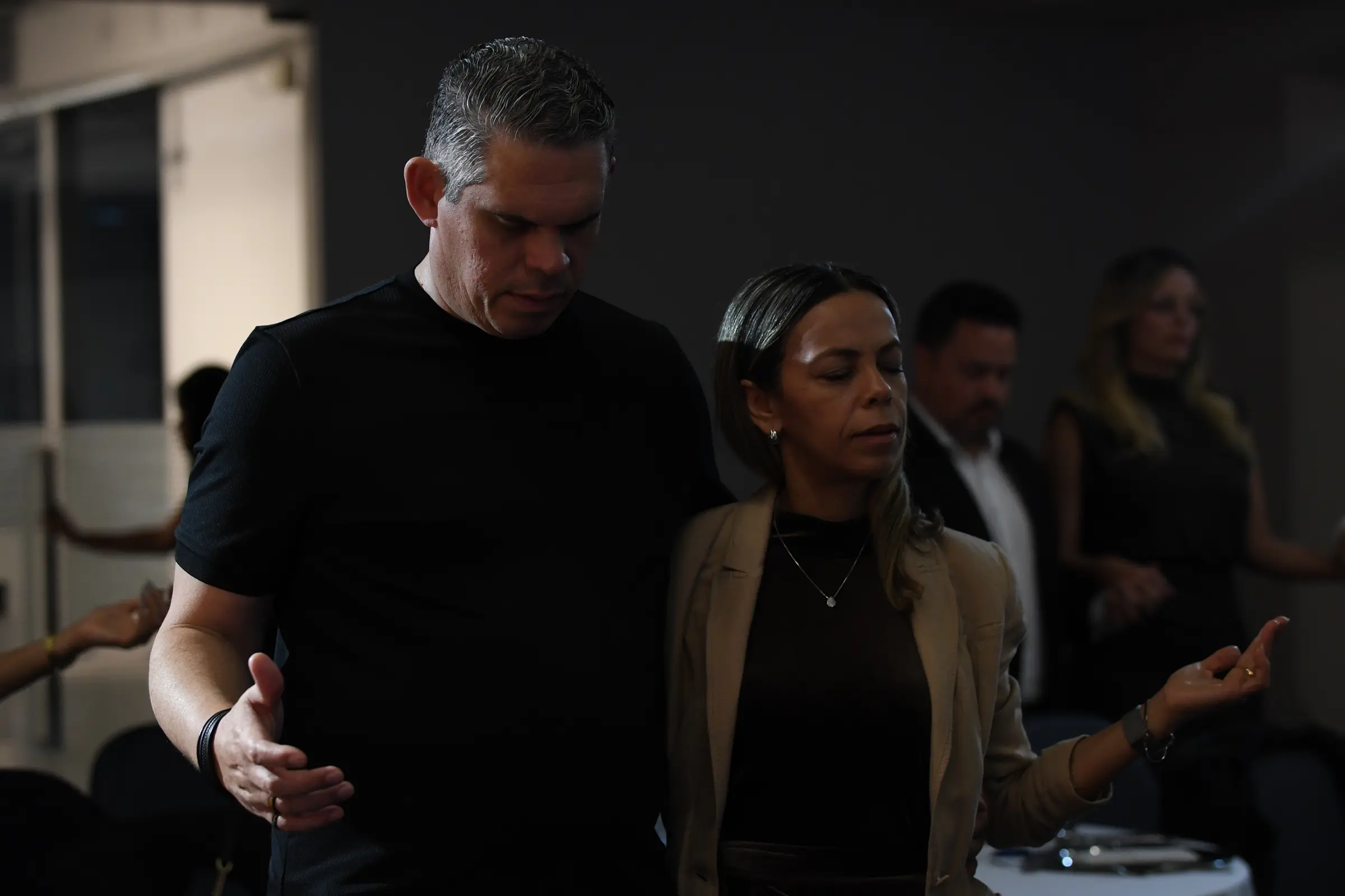 Casal em oração, de olhos fechados, durante o jantar